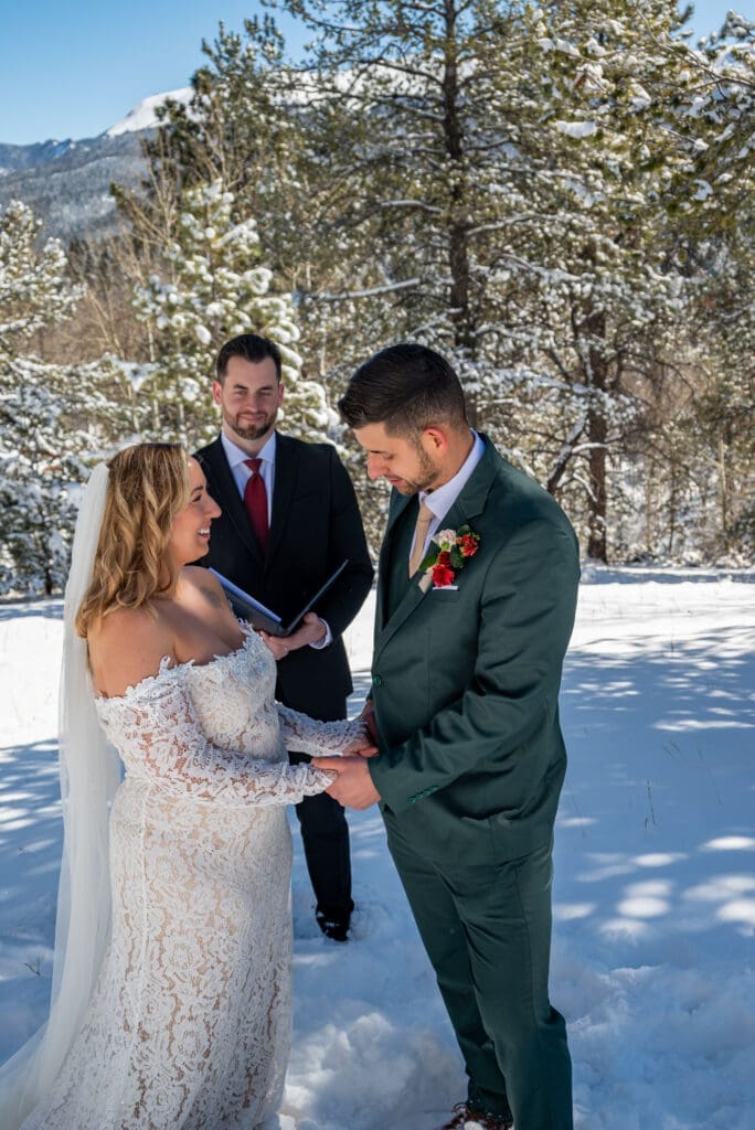 Couple and officiant in Woodland Park in the snow exchanging vows. 