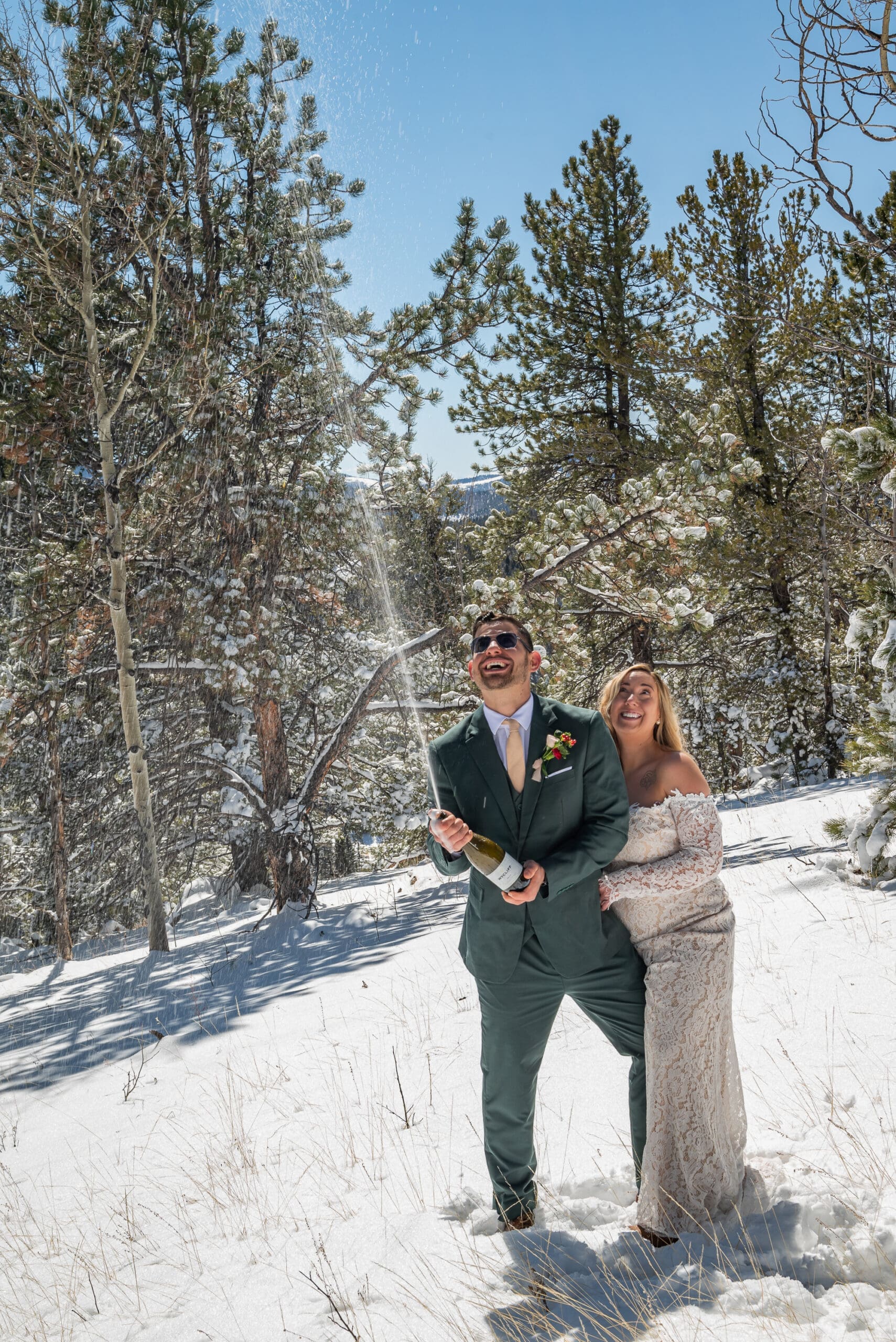 Couple pops champagne in the sun and snow to celebrate getting eloped in Colorado.