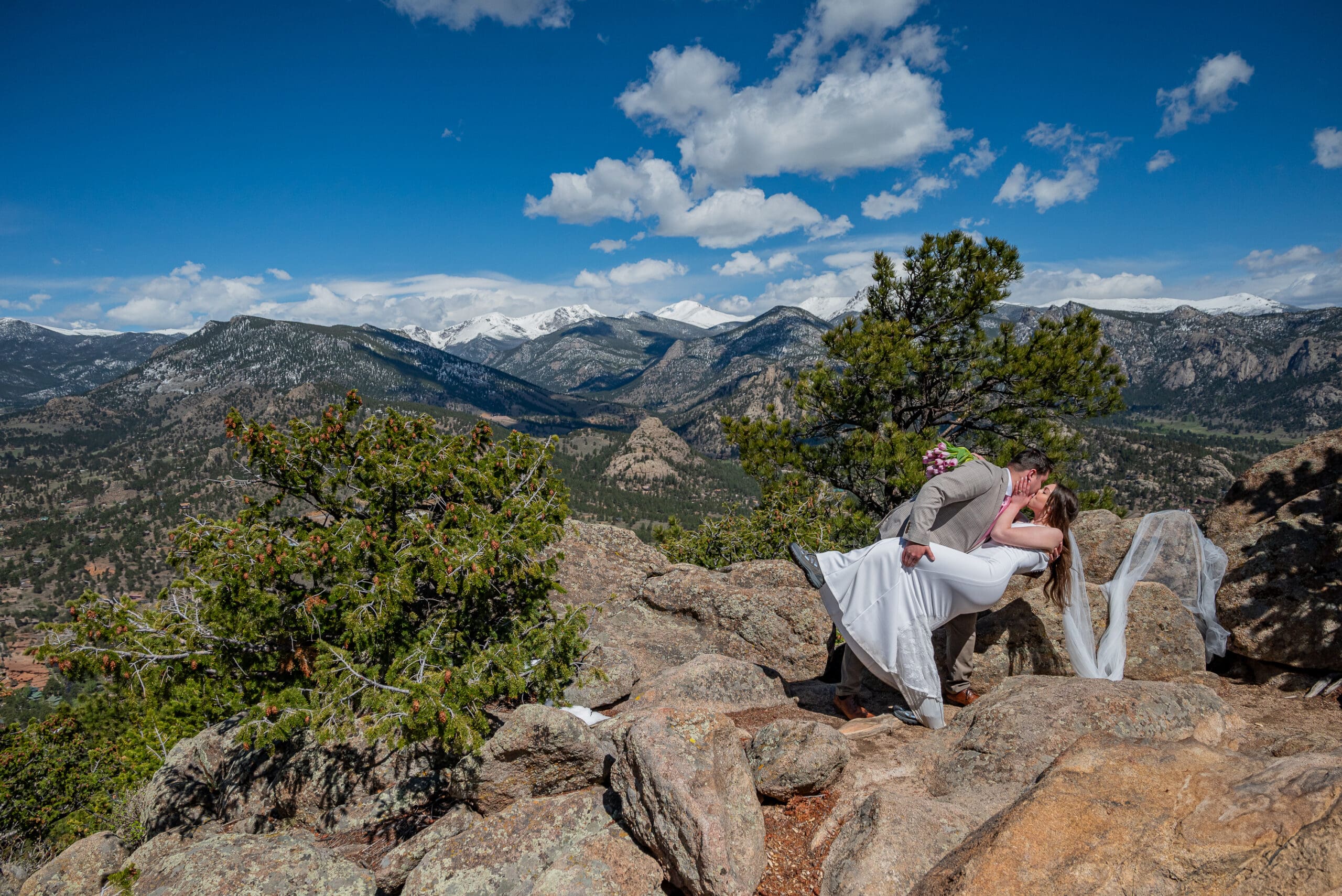 Newly eloped couple does a dip on the top of a ridge overlooking Estes Park, CO.