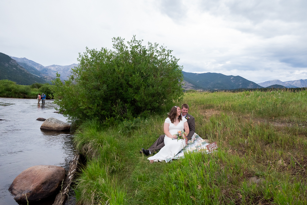 Last Minute Elopement in estes park, CO. Couple sits at their picnic blanket with cake to celebrate getting married.